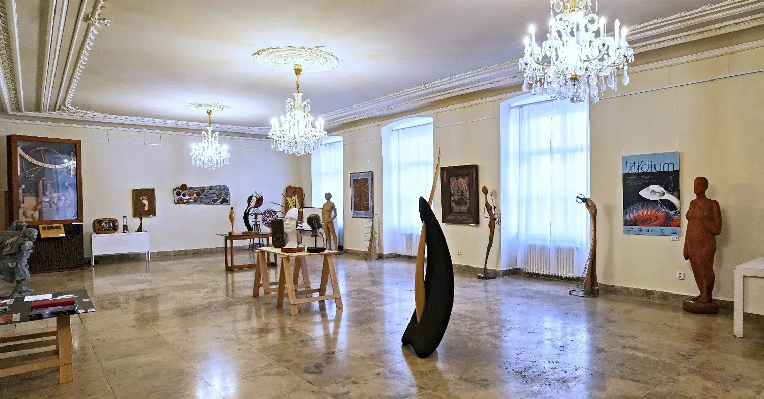 Expozice výstavy Vividium v Justiho síni Primaciálního paláce — sochy pod křišťálovými lustry