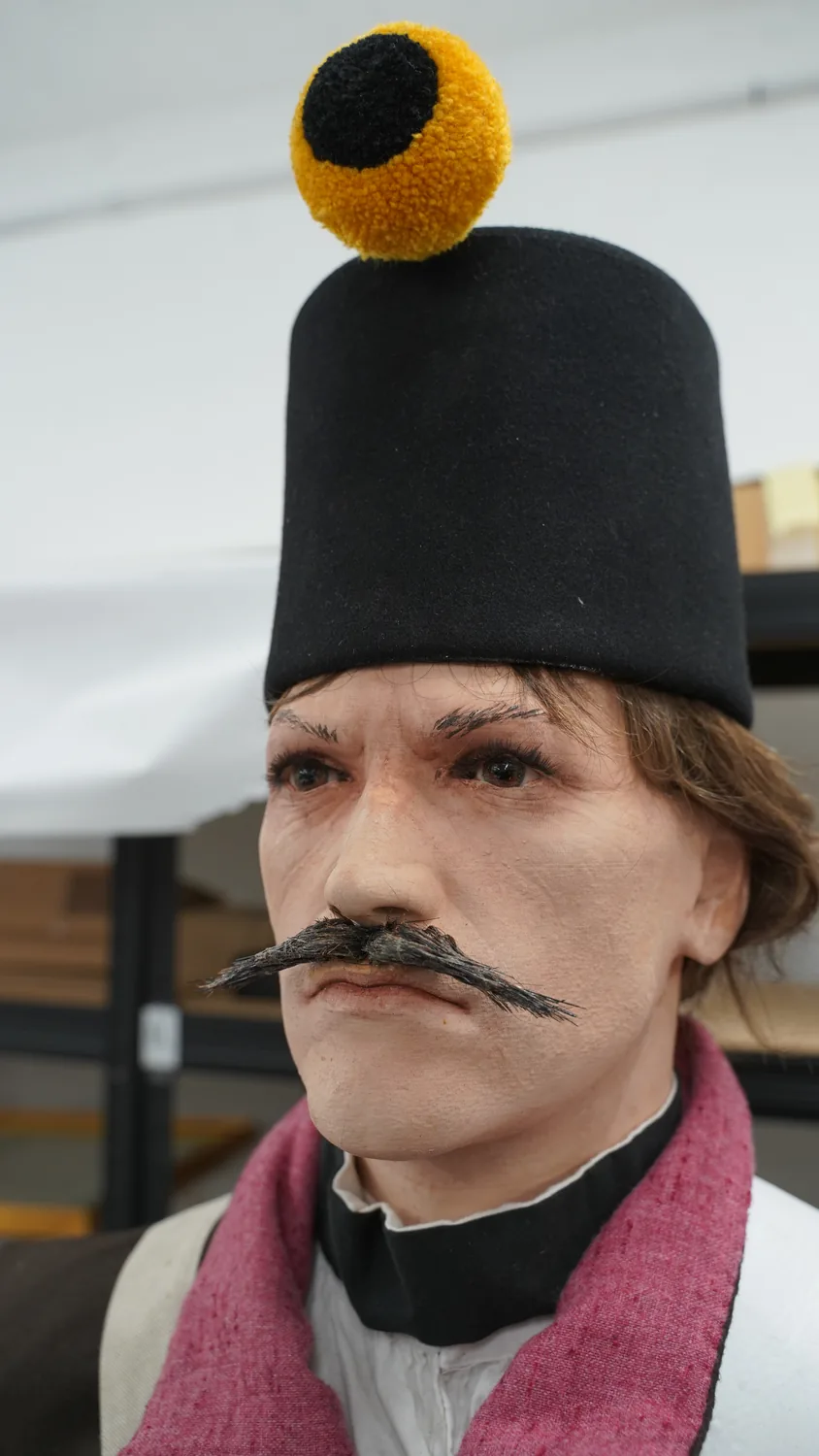 Hlava figuríny muže s knírem v dobové čepici
